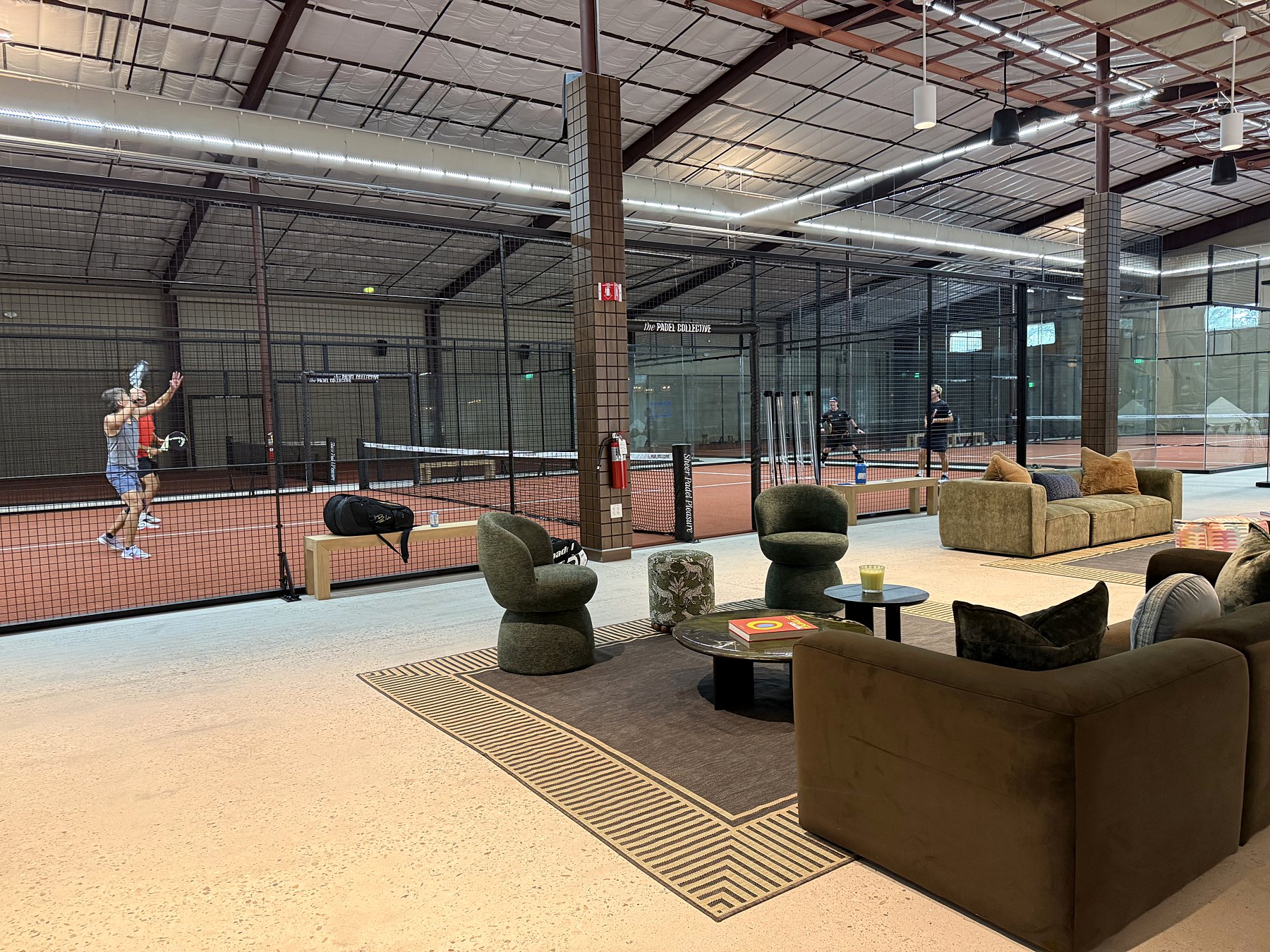 The lounge at the Padel Collective, with a match on the courts behind
