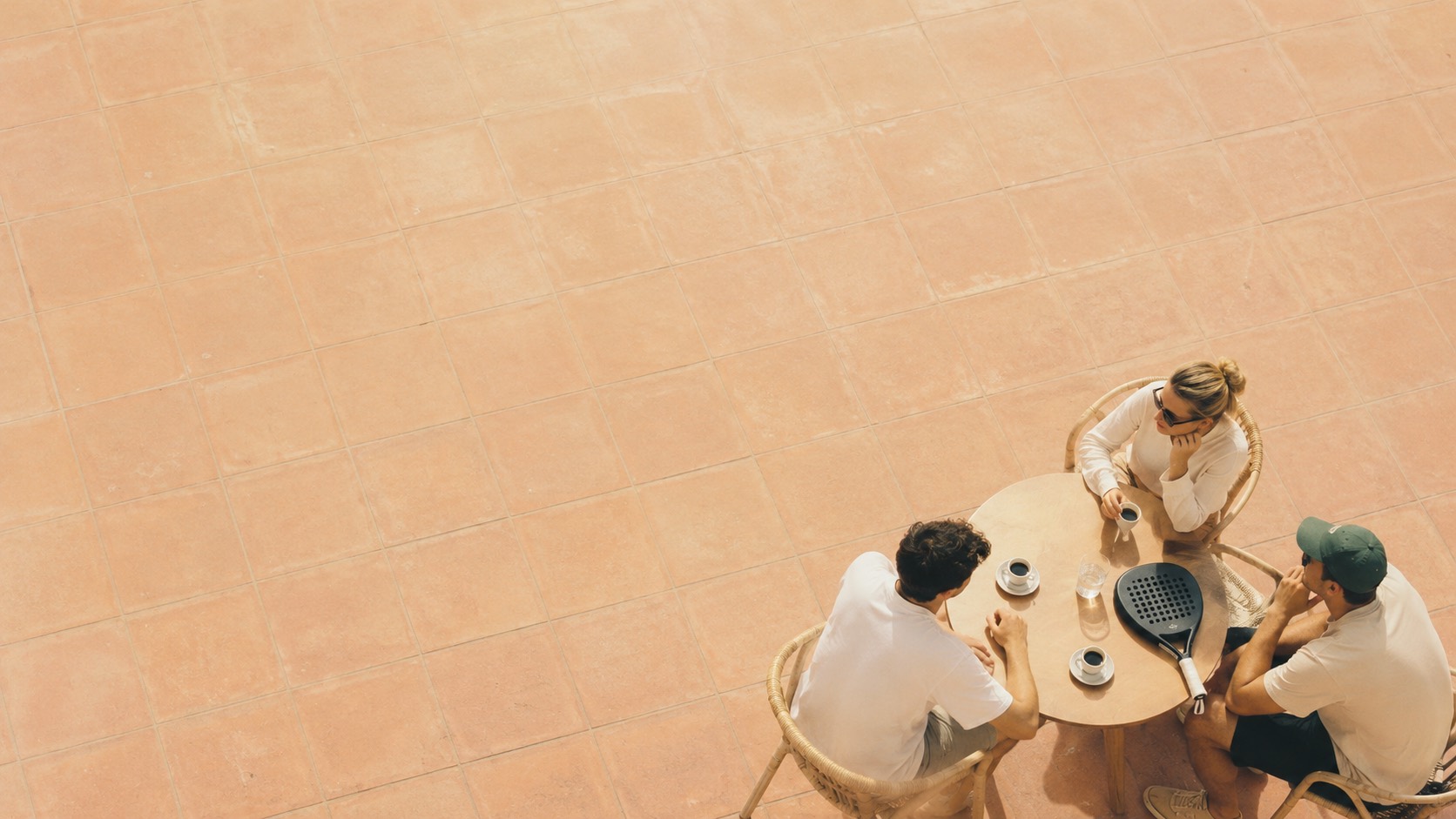 Guests over coffee on a sunlit terracotta terrace at the Padel Collective.